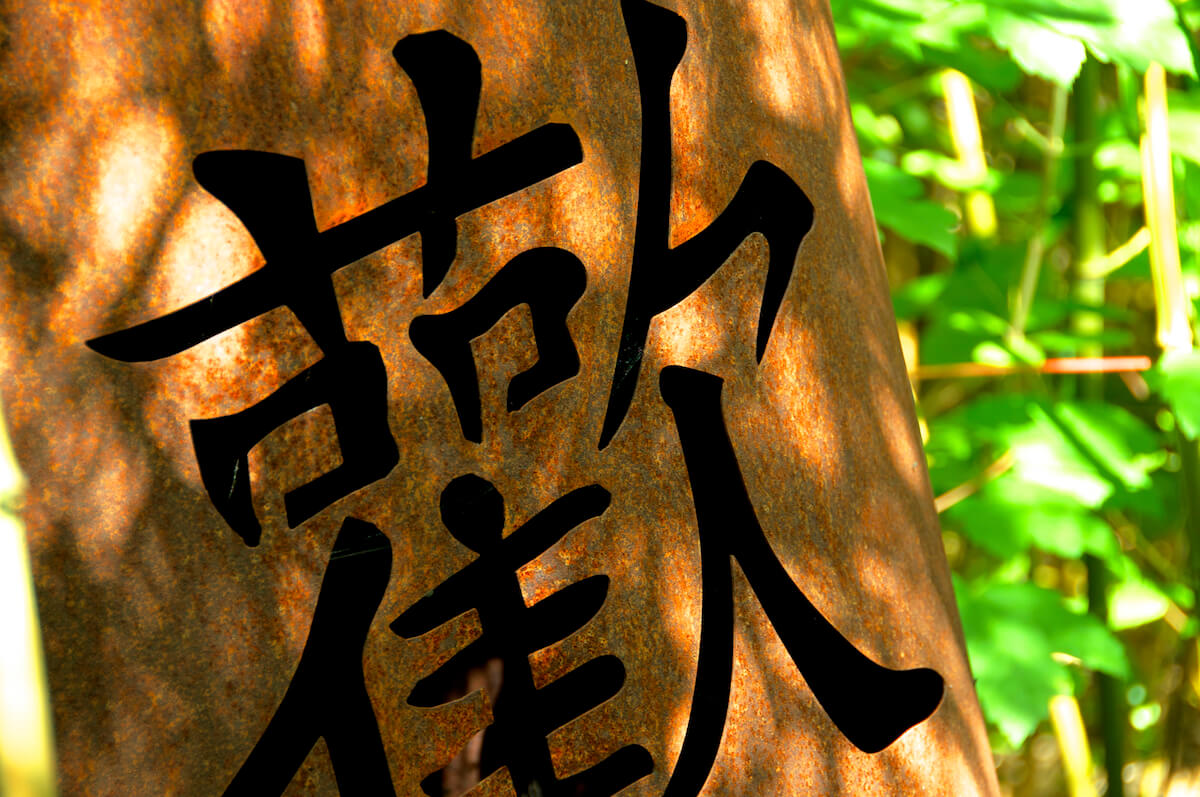 Rostiges Metall-Kunstwerk mit asiatischen Schriftzeichen im Bayerwaldhof-Garten