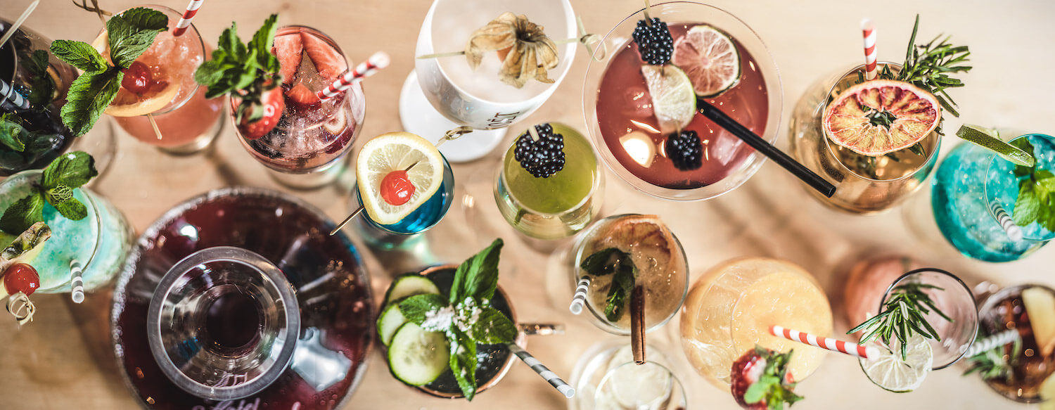 Ansicht von oben: Auswahl bunter Cocktails mit Deko auf der Bar