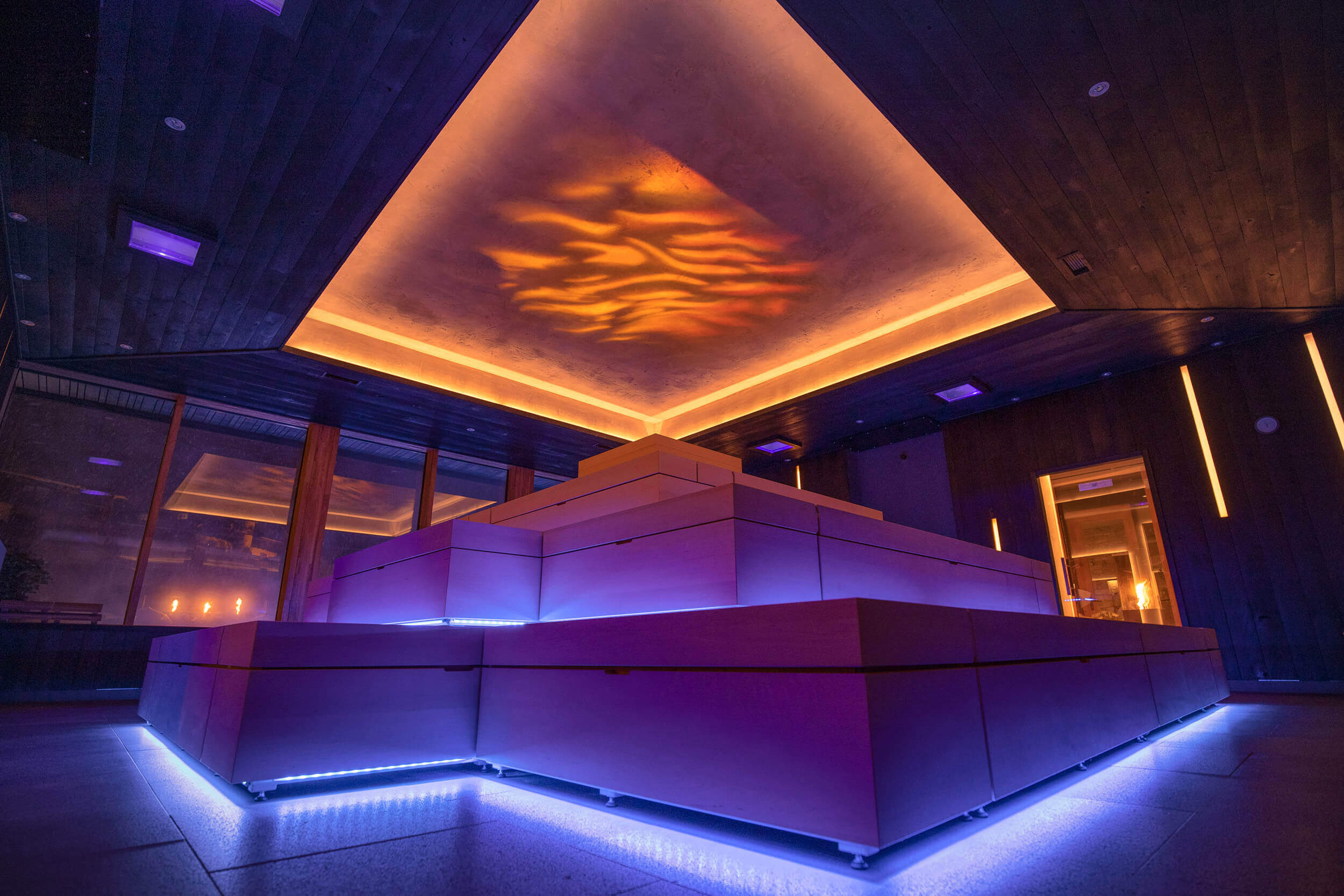 Finnische Sauna mit warmem Licht und atmosphärischer Beleuchtung, dunkles Holz und stimmungsvolle Deckengestaltung