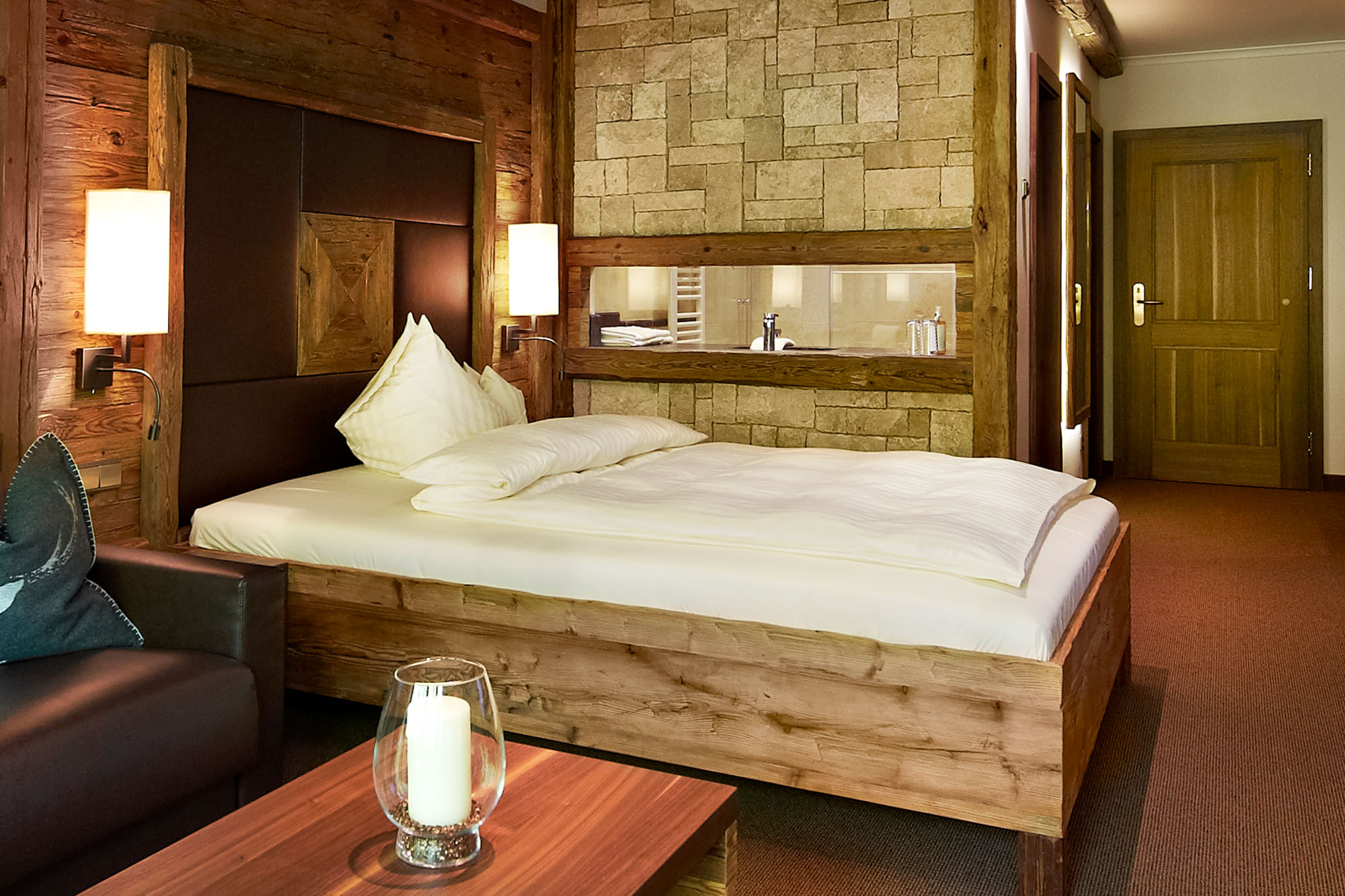Modernes Hotelzimmer mit rustikalem Holzbett, Steinwand und warmer Beleuchtung