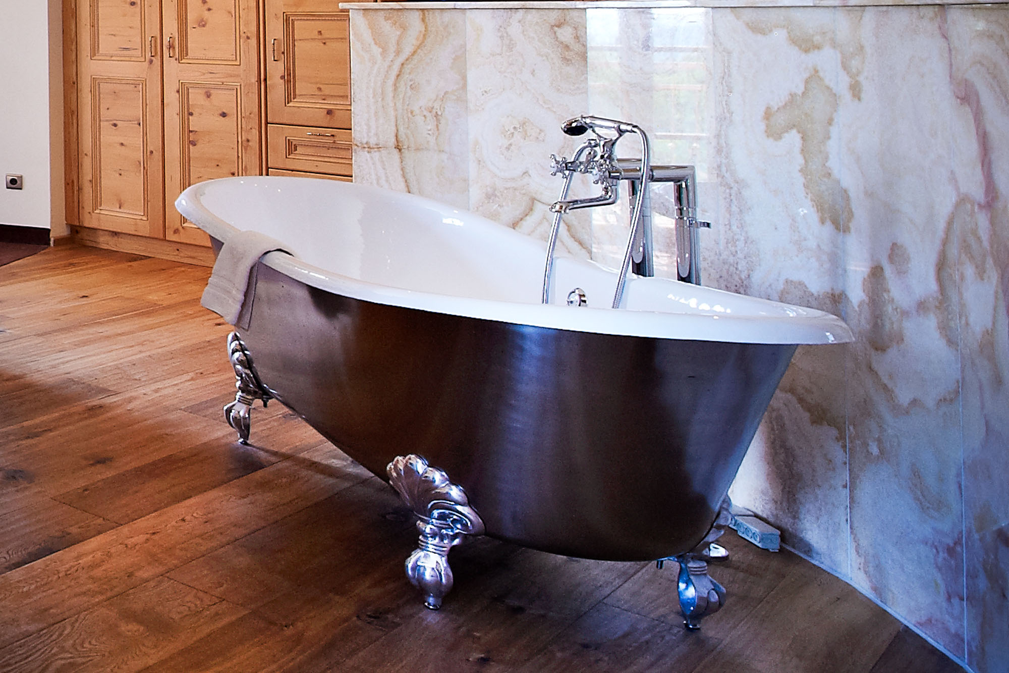 Freistehende Vintage-Badewanne mit Klauenfüßen vor gemusterten Wand