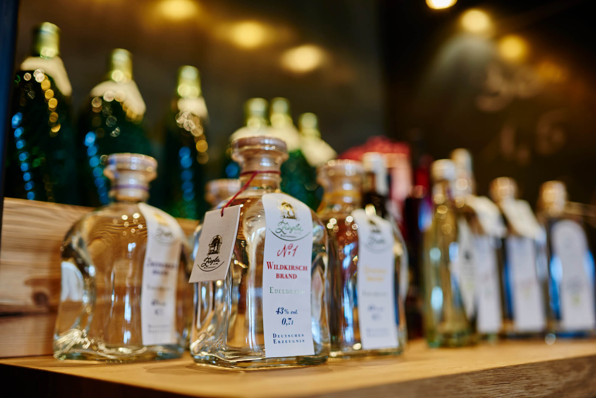 Bild 1: "Gemütliche Hotelbar im Bayerwaldhof mit warmer Beleuchtung" Bild 2: "Auswahl regionaler Spirituosen und Getränke an der Bayerwaldhof-Bar"