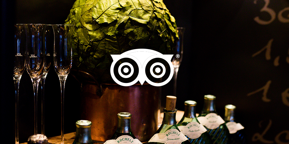 Edle Weinflaschen und Kristallgläser mit Tripadvisor Logo davor